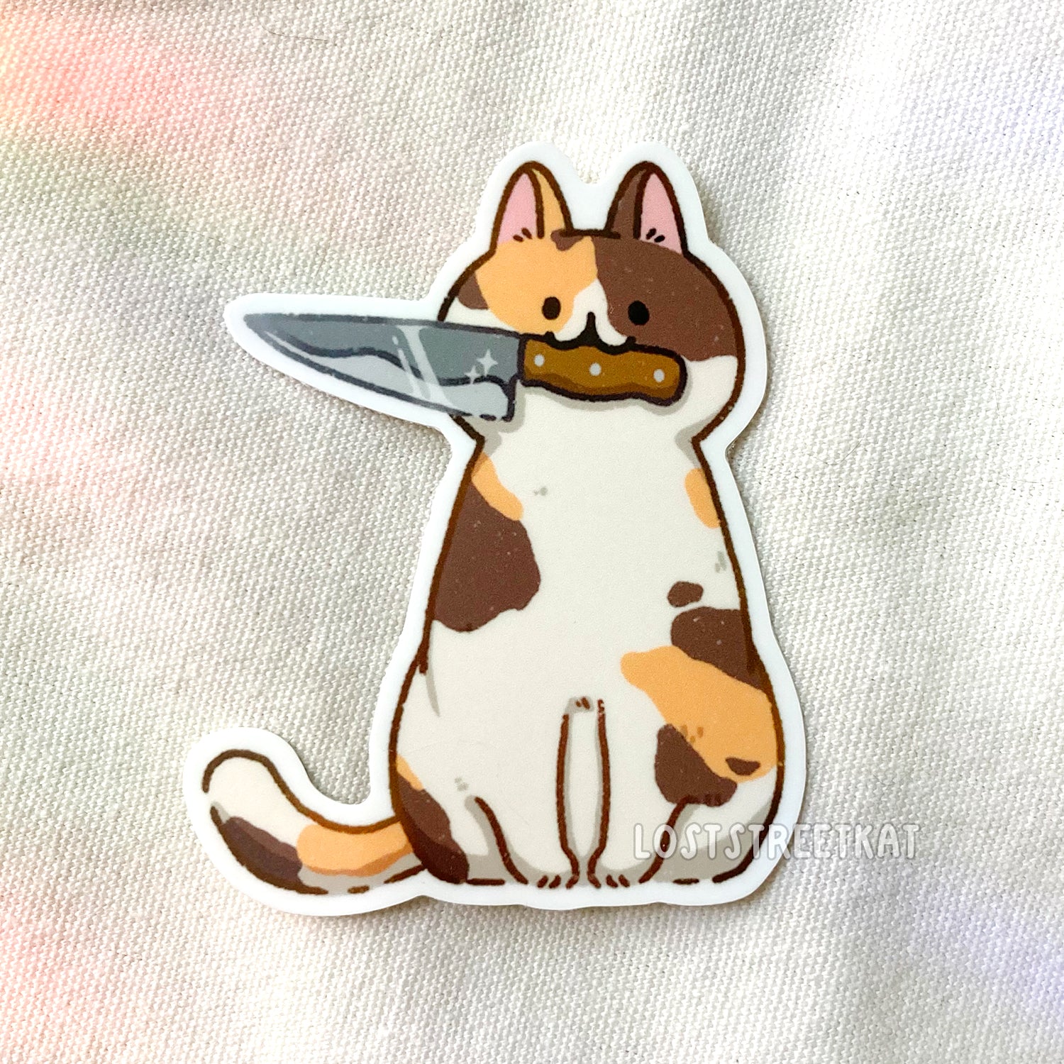 Sitting calico cat holding a knife in mouth vinyl sticker