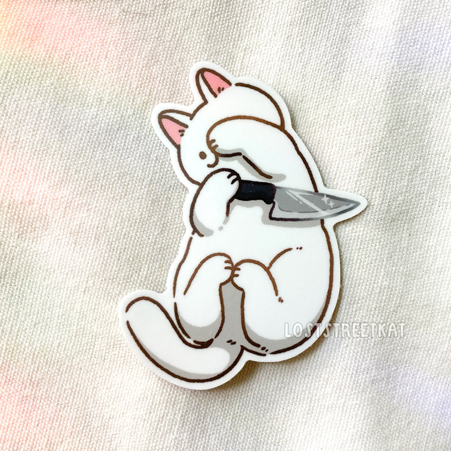White cat with knife in paw, laying back and half covering face vinyl sticker